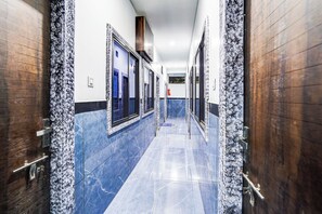A hallway with marble flooring and wooden doors, leading to restrooms.