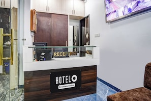 En receptionsdisk med et skilt der står 'RECEPTION' og 'HOTELO', der angiver et hotel med virksomhedsservice.