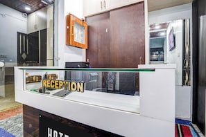 A reception desk with a glass partition, a wooden cabinet above, and a sign that reads 'RECEPTION'.