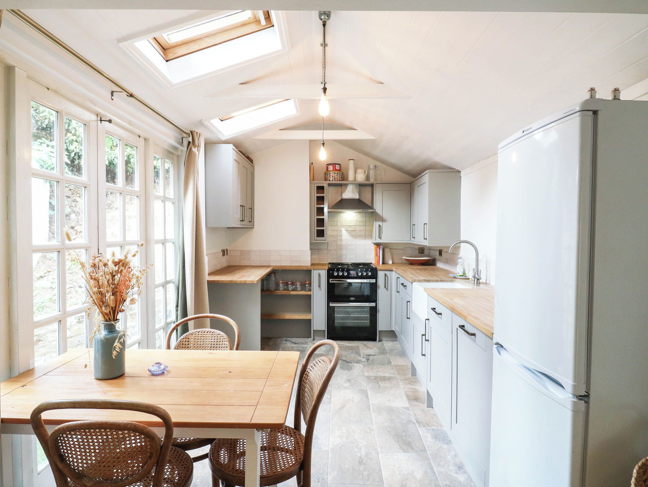 A kitchen with a dining table, chairs, a stove, oven, and a refrigerator.
