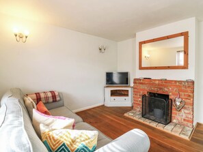 Ein Wohnzimmer mit einer Couch, einem Fernseher, einem Kamin und einem Spiegel an der Wand.