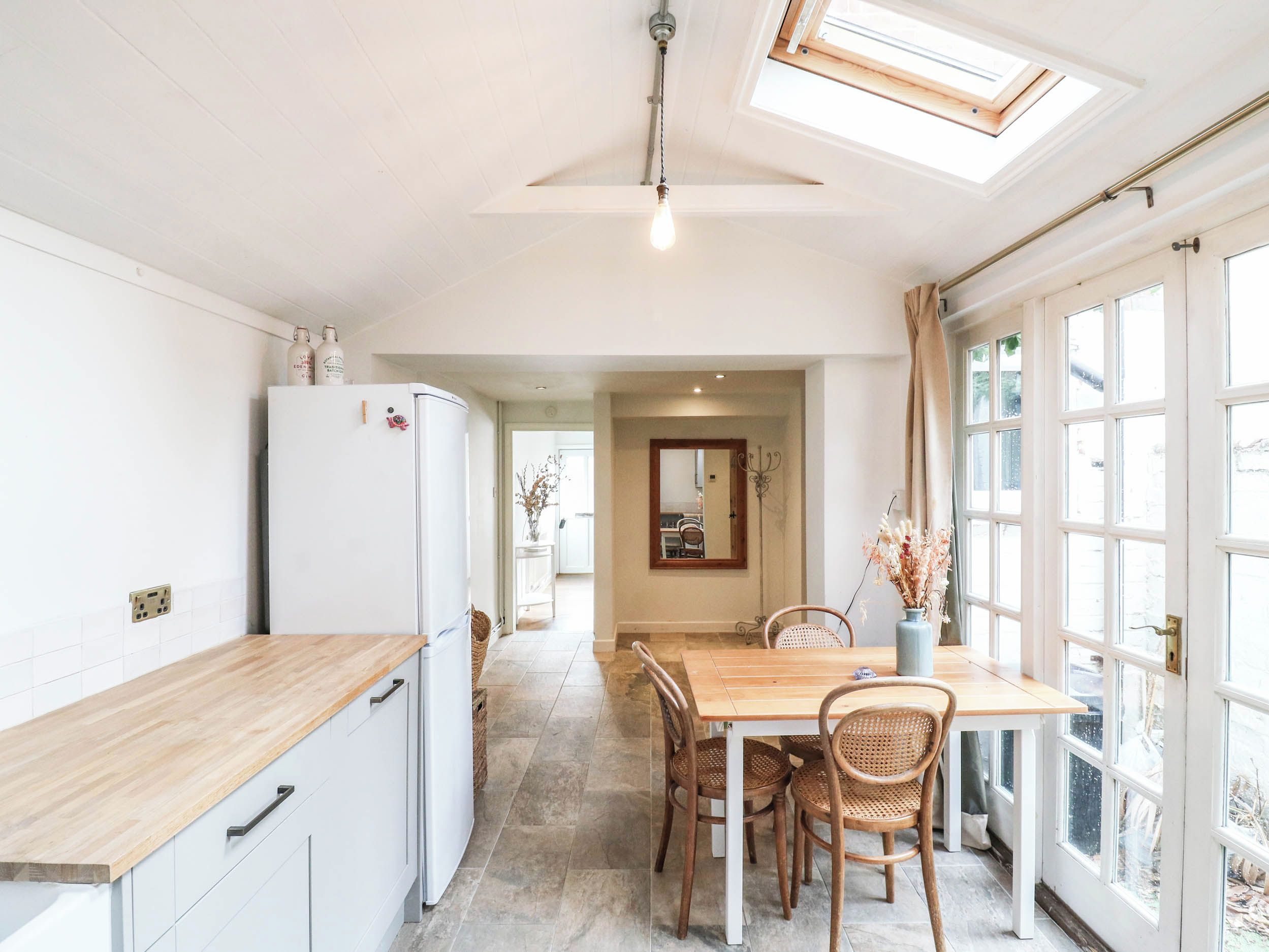 A kitchen with a white refrigerator, wooden countertop, and a dining area with a table and chairs.