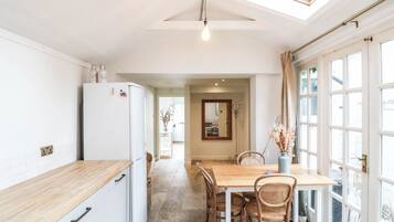 A kitchen with a white refrigerator, wooden countertop, and a dining area with a table and chairs.