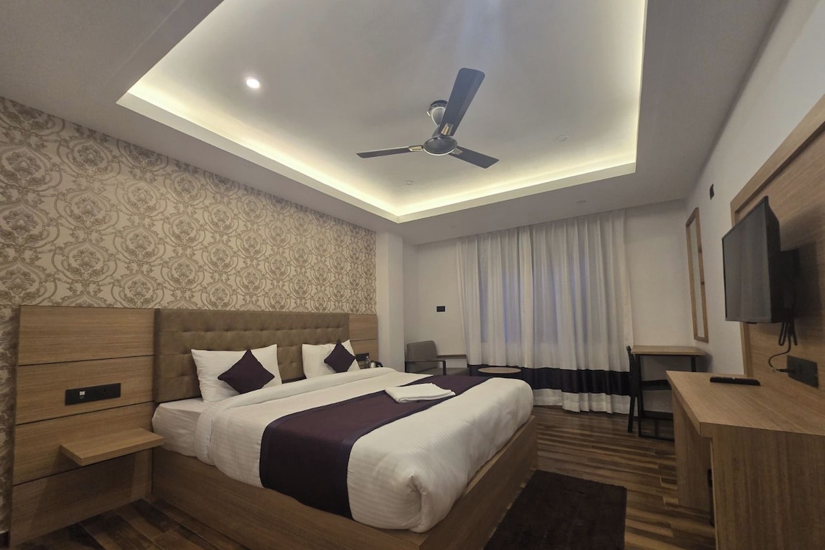 Una habitación de hotel moderna con cama, escritorio, ventilador de techo y televisión.