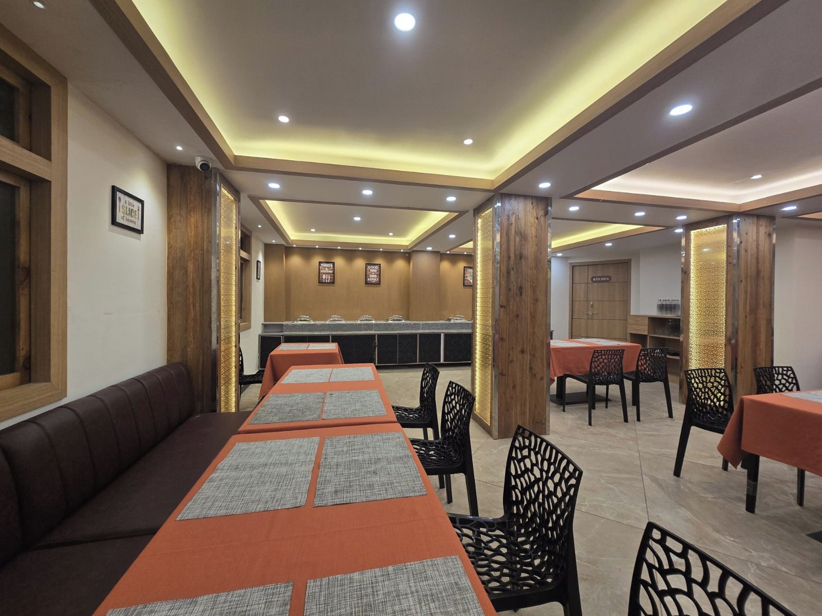 Un restaurante con una larga mesa común, mesas individuales y una zona de estar con sofás.
