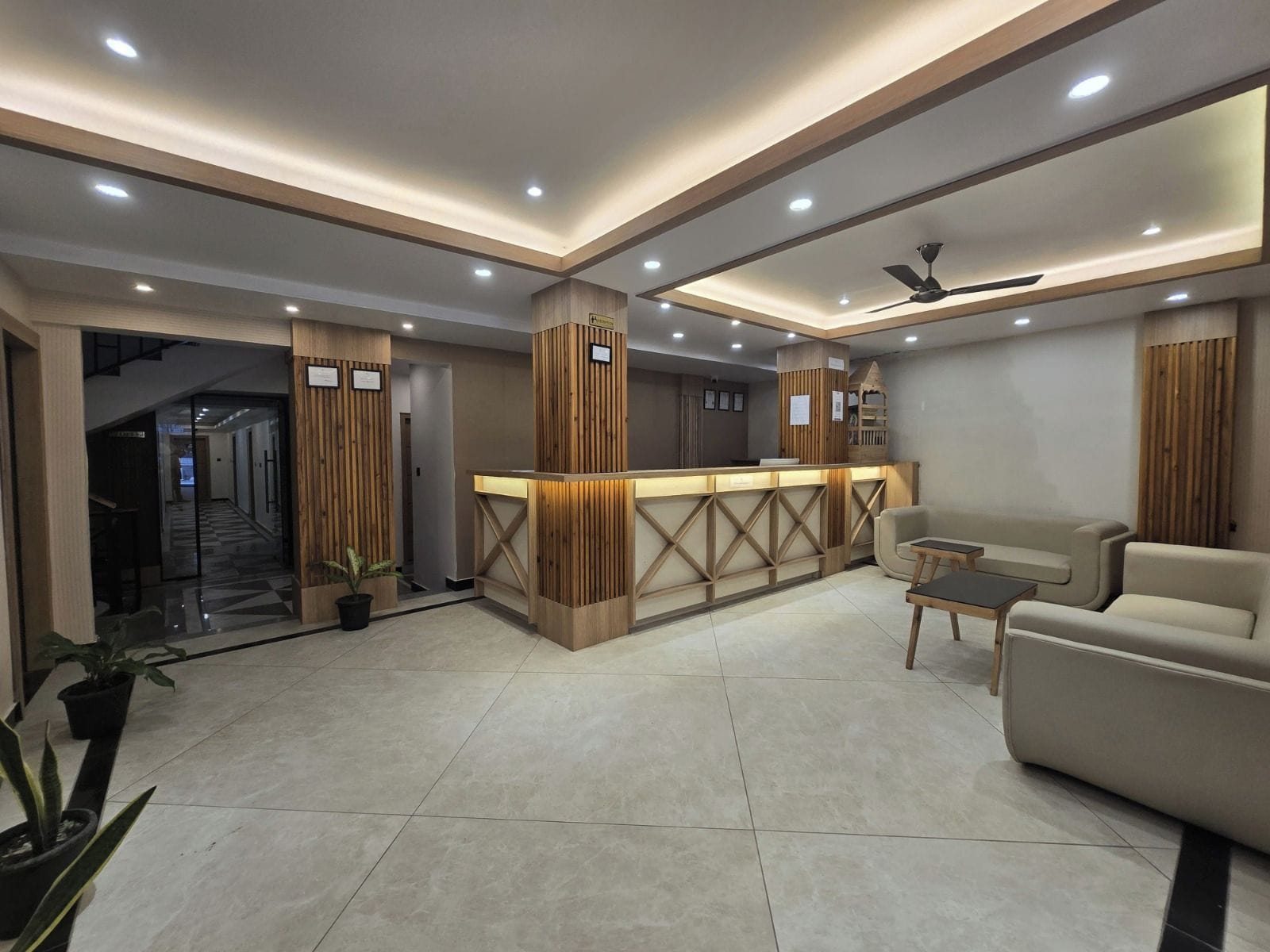 Un área de recepción moderna con un mostrador de madera, zona de estar y un ventilador de techo.