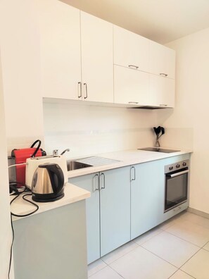 A modern kitchen with white cabinets, a stainless steel kettle, a red toaster, and a built-in oven. - Convenient studio with Wi-Fi near Nice city centre (Nice)