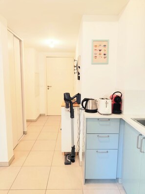 A compact kitchen with a toaster, kettle, and a coffee maker on the counter, a small cabinet with drawers, and a door leading to another room. - Convenient studio with Wi-Fi near Nice city centre (Nice)