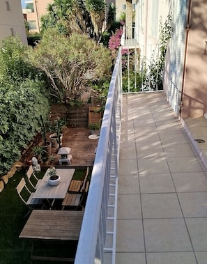 Ein Balkon mit Blick auf einen Garten, Gartenmöbel und eine Statue.
