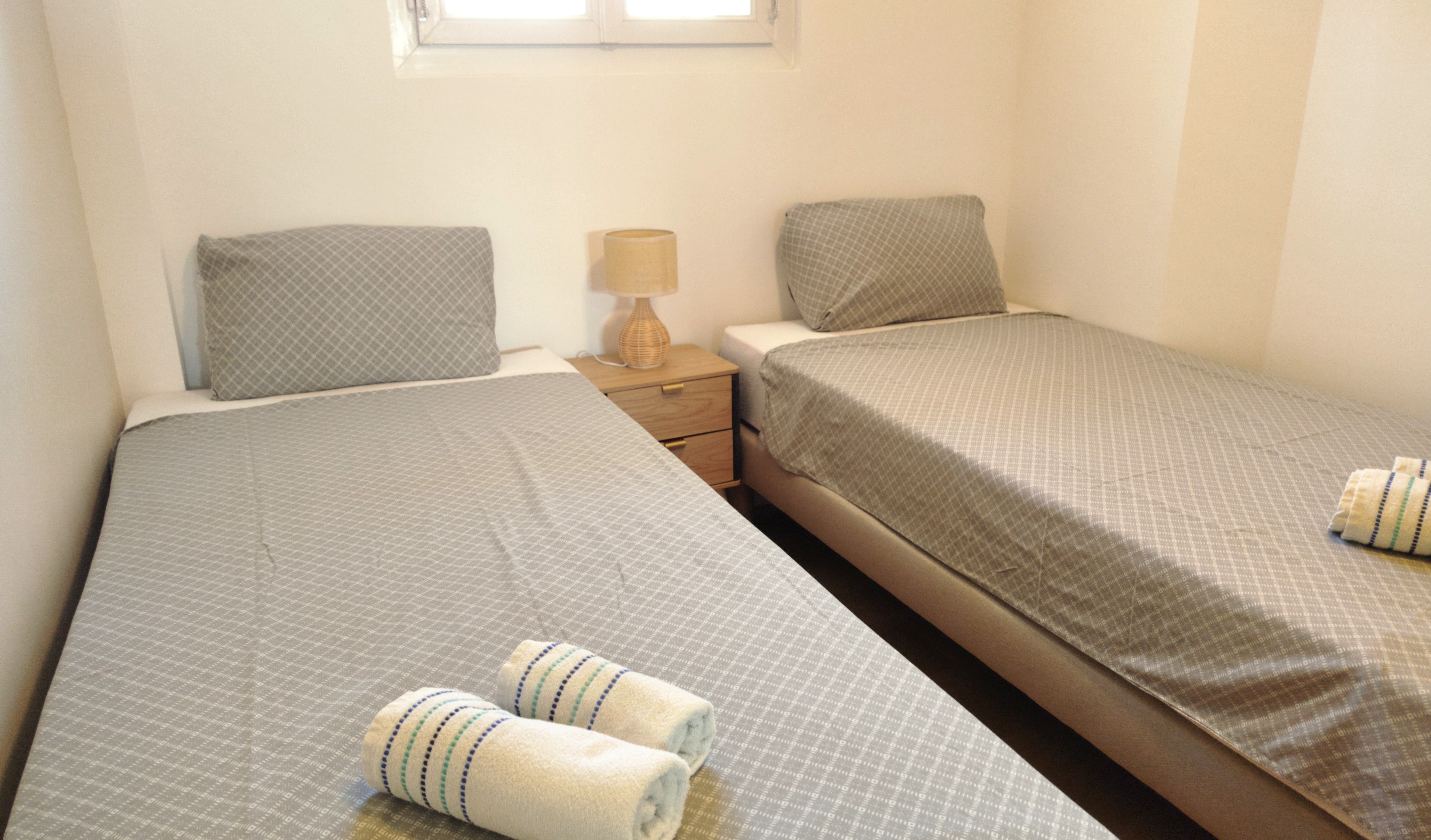 Ein Doppelzimmer mit zwei Betten, einem Nachttisch und einer Lampe.