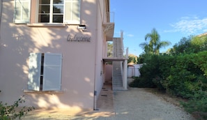 Ein Gebäude mit einem Namensschild, einem Balkon und einem Garten.