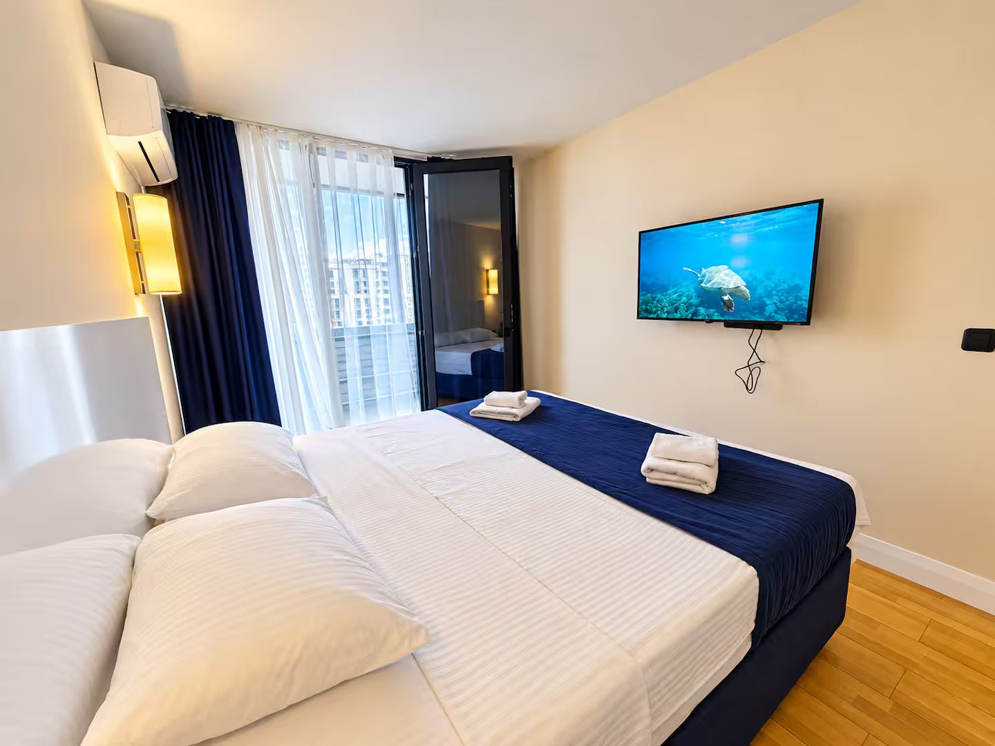 Une chambre d’hôtel avec un lit, une télévision, une fenêtre avec des rideaux et une vue sur la ville.