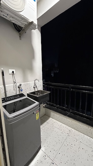Eine kleine Küchenzeile mit Spüle, Waschmaschine und Ventilator.