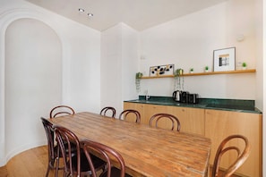 A dining area with a wooden table and chairs, a kitchen with a green countertop, and a shelf with decorative items. - Spacious Apartment 3br/8p - Opera (Paris)