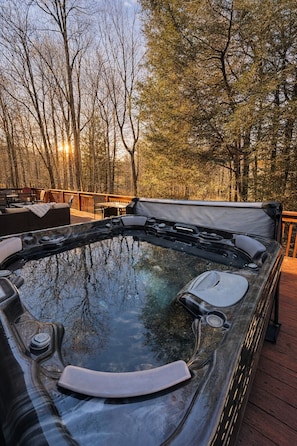 Ein Whirlpool auf einer Holterrasse mit Blick auf Bäume und einen Sonnenuntergang.