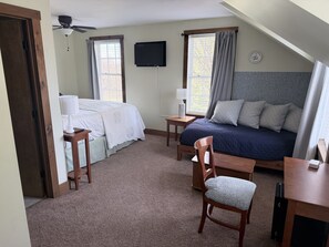 Un dormitorio con cama, escritorio, silla, televisión y ventilador de techo.
