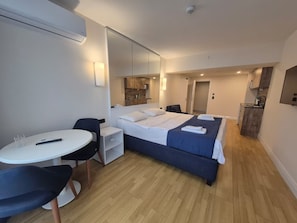 Habitación de hotel con cama, escritorio, silla, una mesita y un espejo.