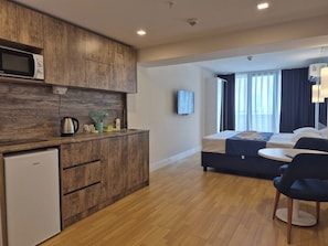 Une chambre d’hôtel moderne équipée d’une kitchenette, d’un lit, d’une télévision et offrant une vue sur la ville.