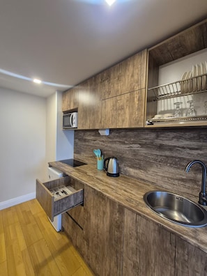 Una cocina moderna con armarios de madera, un lavamanos de acero inoxidable y un microondas integrado.