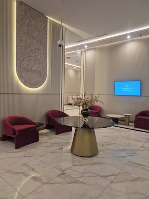 Eine moderne Lobby mit Marmorboden, einem runden Tisch in der Mitte und roten Sitzmöbeln.