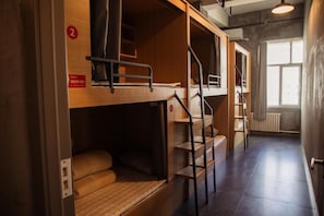 Un dormitorio con literas, una escalera y una ventana que proporciona luz natural.