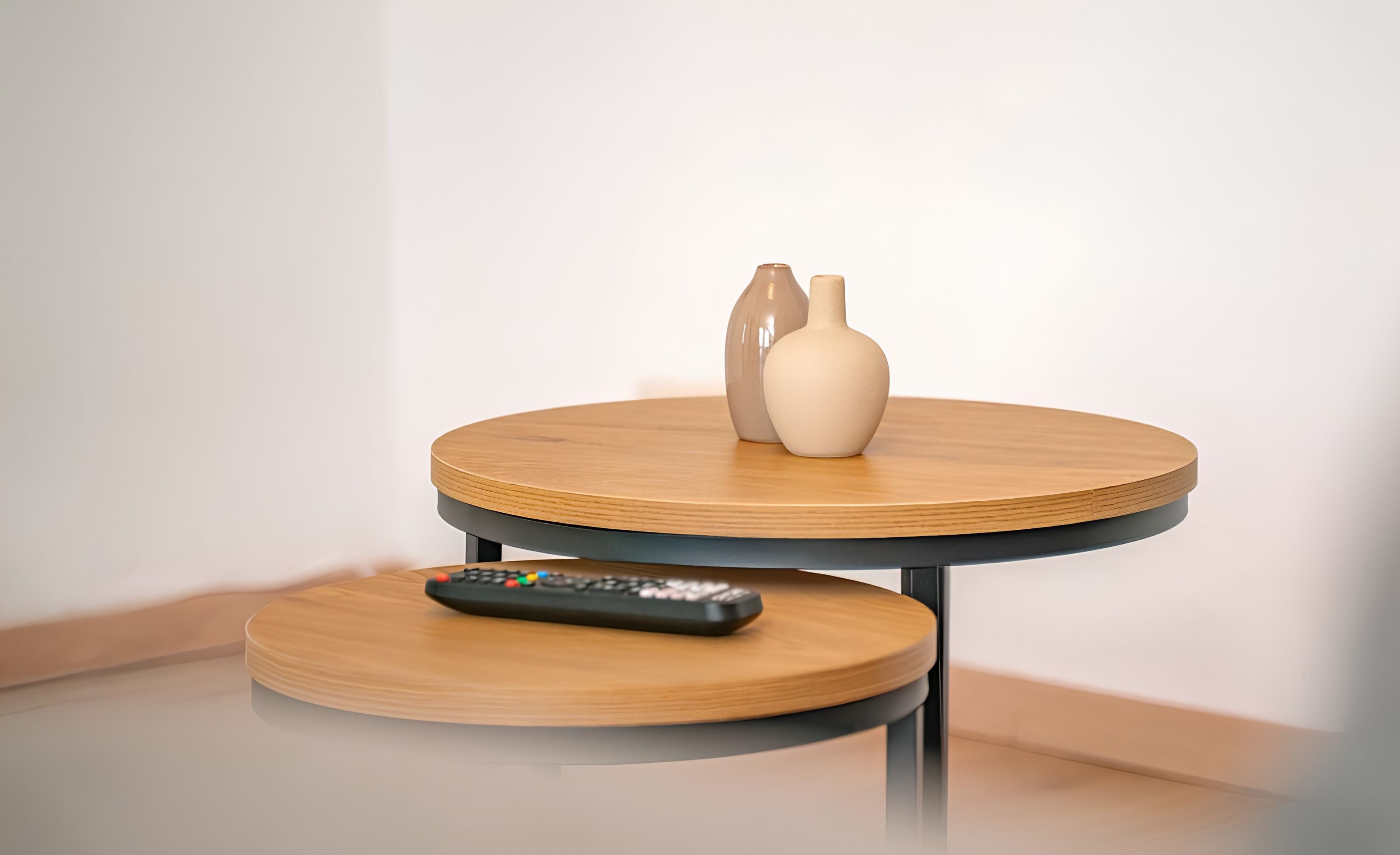 Une table ronde en bois avec une télécommande posée sur une petite plateforme inférieure.