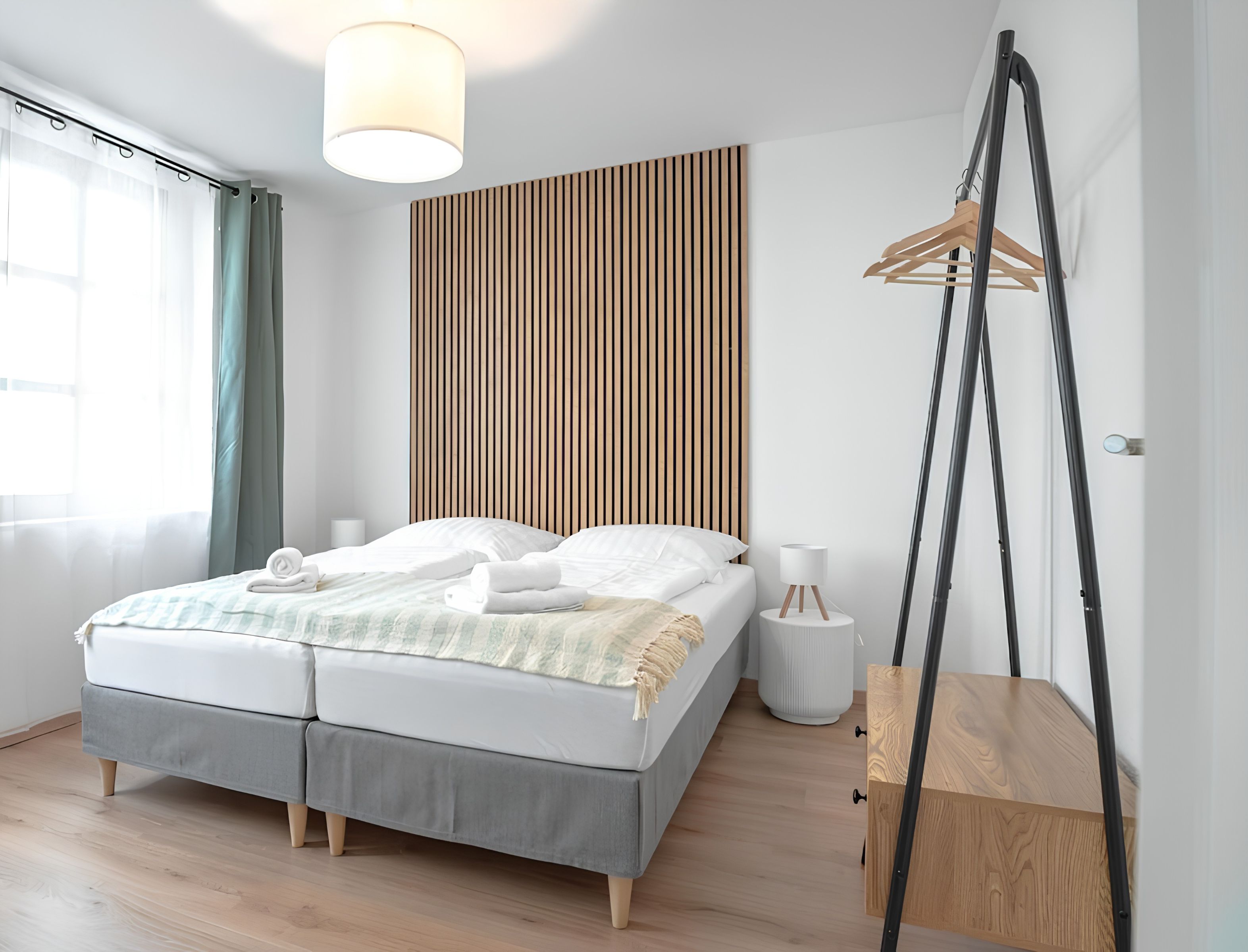 Ein modernes Schlafzimmer mit Bett, Nachttisch und einer Pendelleuchte.