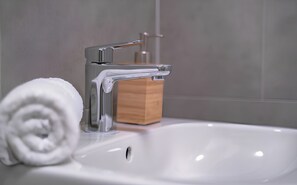 Un bany amb un rentatge blanc, una tovallola i un dosificador de sabó.