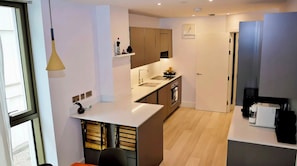 A modern kitchen with a central island, built-in appliances, and a pendant light. - The Warwick Lane Residences by Aureva (London)