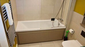 A bathroom with a bathtub, toilet, and towel rack. - The Warwick Lane Residences by Aureva (London)