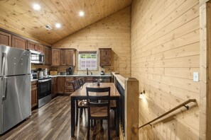 Eine Küche mit Holzwänden, einem Edelstahlkühlschrank, einer Mikrowelle und einem Herd.