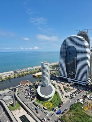 Ein modernes Hotel mit einer markanten, gebogenen Fassade, einer zentralen zylindrischen Struktur und Blick aufs Meer.