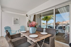 Een eethoek met een houten tafel, rieten stoelen en een vaas bloemen.