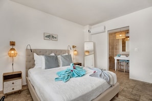 A hotel room with a bed, bedside lamps, a mirror, and a bathroom visible through an open door. - Ground-Floor 1BR, Marina View, Sleeps 3 · Apt 22 Ocean Breeze (Kralendijk)