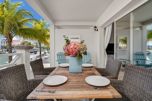 A dining area with a wooden table, white plates, and a vase of flowers. - Ground-Floor 1BR, Marina View, Sleeps 3 · Apt 22 Ocean Breeze (Kralendijk)