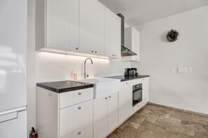 Een moderne keuken met witte kastjes, een zwart aanrecht, een roestvrijstalen spoelbak en een inbouwoven.
