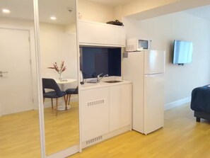 Una kitchenette compacta con microondas, refrigerador y lavamanos.