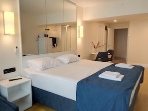 Una habitación de hotel con una cama grande, mesitas de noche, un escritorio y una silla.