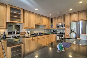 A modern kitchen with wooden cabinets, stainless steel appliances, and a granite countertop. - Walk to Beach:  Waterfront Condo in Ocean City! (Ocean City)