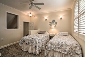 A bedroom with two beds, a ceiling fan, wall sconces, and a window with blinds. - Walk to Beach:  Waterfront Condo in Ocean City! (Ocean City)
