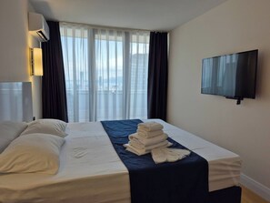 Una habitación de hotel con cama, televisión de pantalla plana y ventana con cortinas.