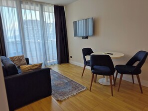 Una sala moderna con un sofá, sillones, un televisor y una mesa de comedor.