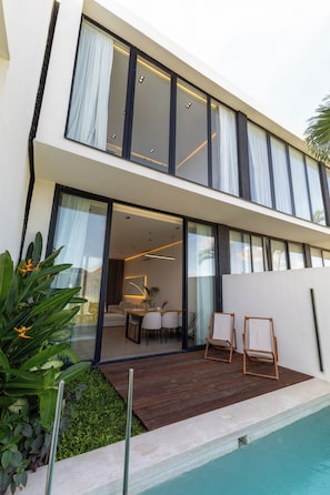 A modern two-story house with a swimming pool, large windows, and a patio area.