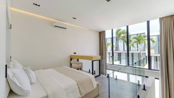 A modern hotel room with a bed, a desk, and a balcony with a view of palm trees.