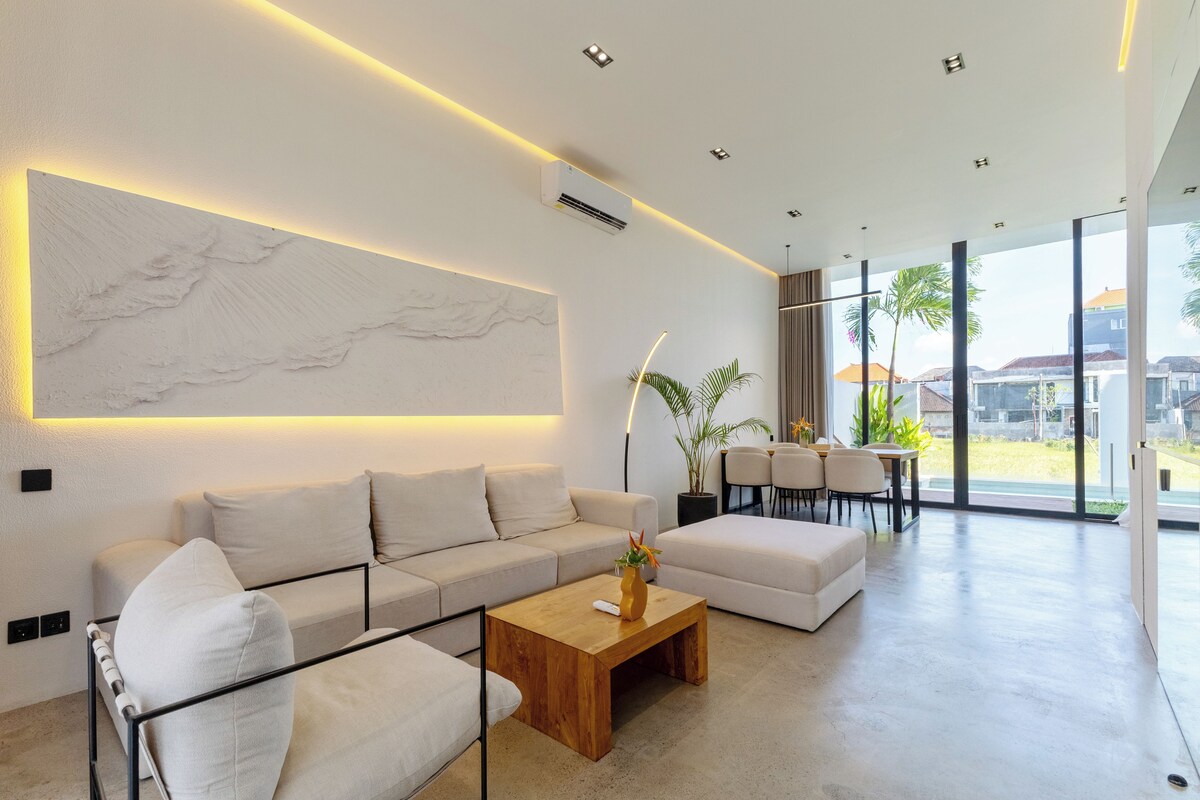 Una sala moderna con un sofá, una mesa de centro y un ventanal con vistas al exterior.