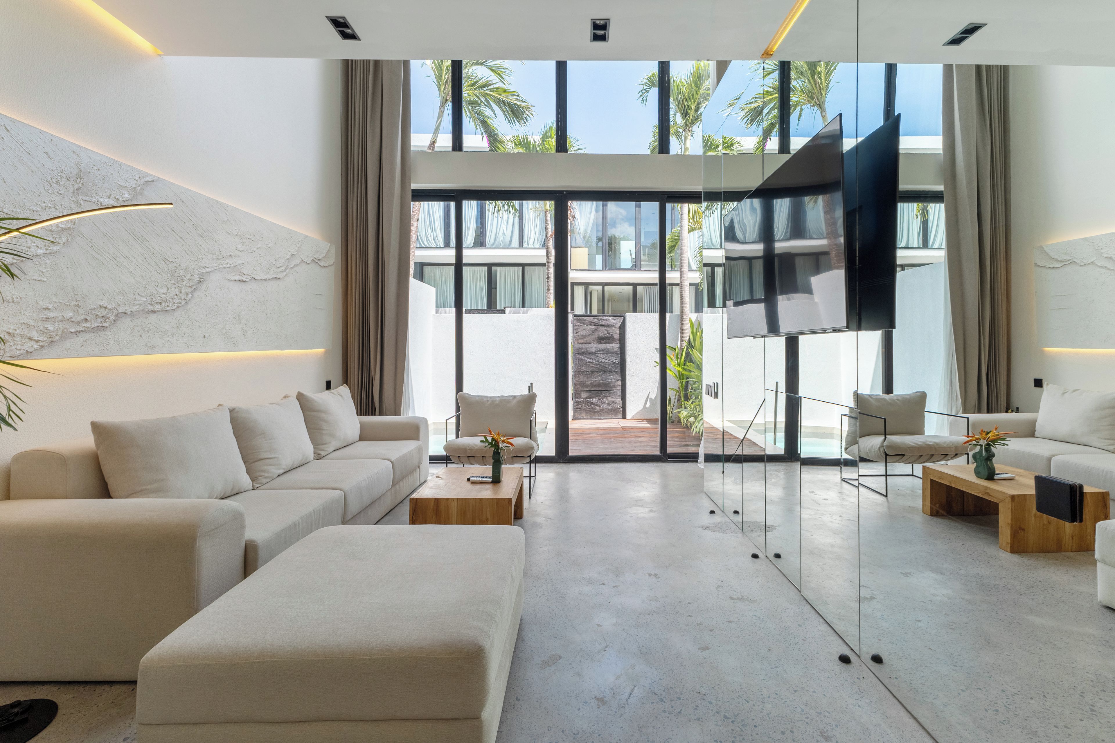 A modern living room with a sofa, armchairs, a coffee table, and a TV.