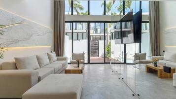 A modern living room with a sofa, armchairs, a coffee table, and a TV.
