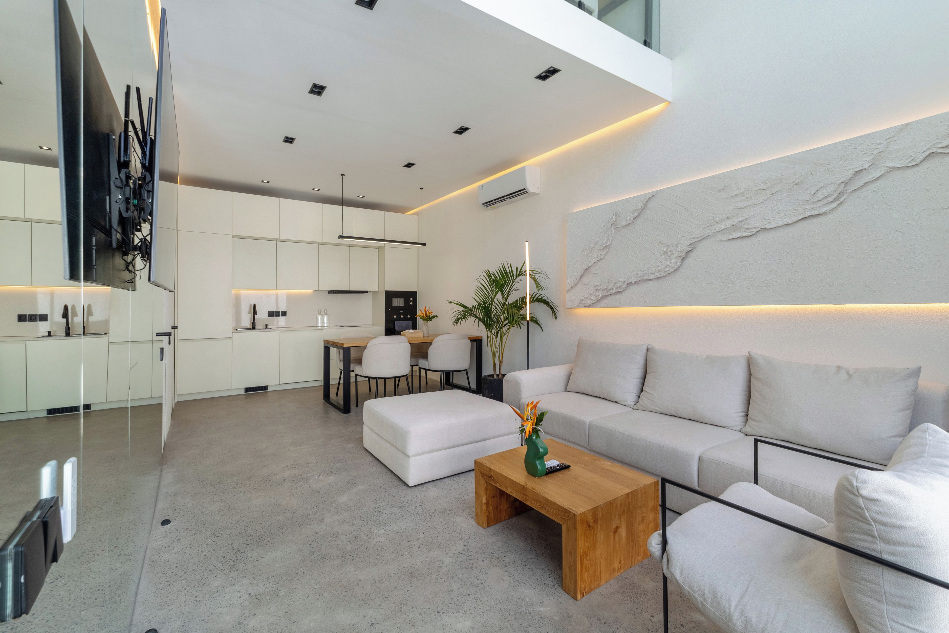 A modern living room with a sofa, coffee table, and a dining area with chairs and a table.
