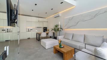 A modern living room with a sofa, coffee table, and a dining area with chairs and a table.
