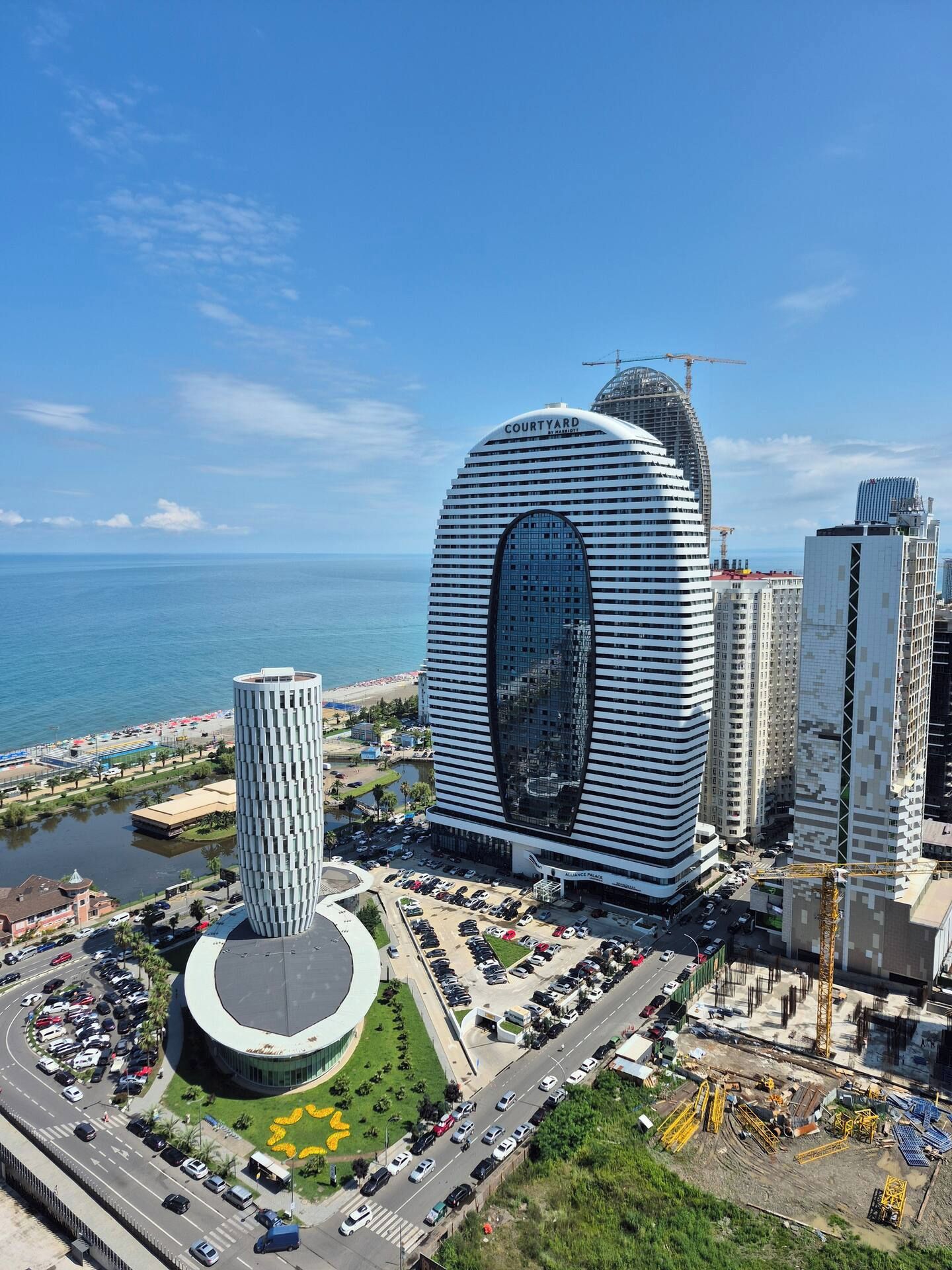 Un hotel moderno con una fachada curva característica, un patio central y vistas al mar.